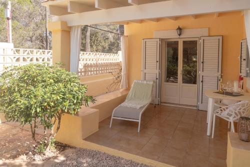 a porch with a bench and a chair and a door at Bungalows Casa Amarilla in Playa Migjorn