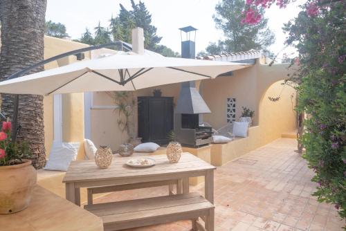 a patio with a table with a white umbrella at Bungalows Casa Amarilla in Playa Migjorn
