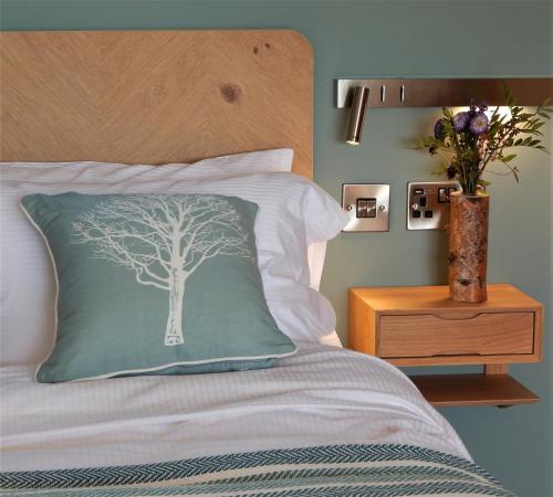 イングルトンにあるThe Lodges at Thornbrookの木の絵が描かれた枕が置かれたベッド