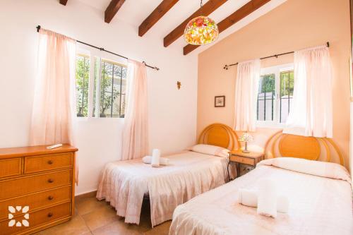 a bedroom with two beds and a dresser and windows at Villa Serenidad by Abahana Villas in Benissa