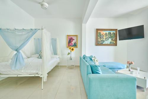 a white bedroom with a bed and a blue couch at Red House on the beach in Punta Rucia