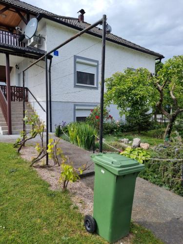 a green trash can in front of a house at Holiday Home in Velika Mlaka