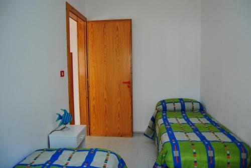 a bedroom with two beds and a wooden door at Casa del Sole pt by Salento Prime in Marina di Pescoluse