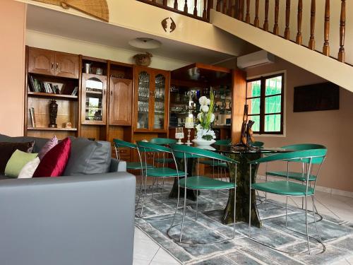 聖多美的住宿－Résidence Gabrielle，一间带桌子和绿色椅子的用餐室