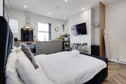 a bedroom with a white bed and a kitchen at Wimbourne Road Apartment 1 in Bournemouth