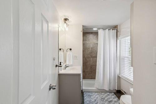a white bathroom with a shower and a sink at Vibrant and Spacious 4bd Home 5 Mins to DT Royal Oak in Royal Oak