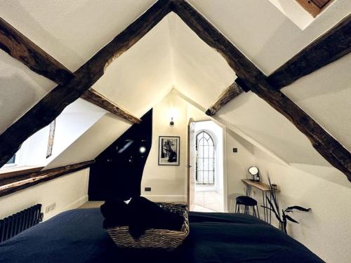 - une chambre avec un lit dans une pièce dotée de poutres dans l'établissement Cotswold Garden Cottage, à Chipping Norton