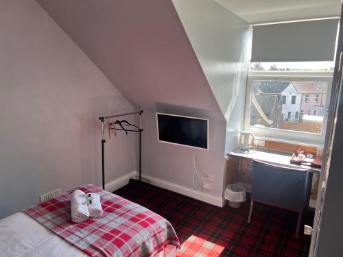 a bedroom with a bed and a desk and a window at Gothenburg Hotel in Rosyth