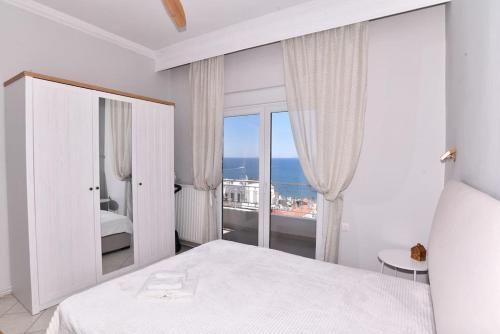 - une chambre avec un lit blanc et une grande fenêtre dans l'établissement Blue Memories, à Kavala