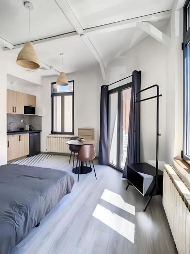une chambre avec un lit, un bureau et une table dans l'établissement La Licorne, grand studio chaleureux, à Amiens