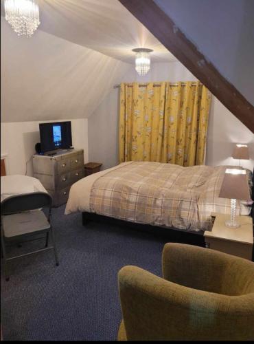 a bedroom with a bed and a tv and a chair at Victorian Gate House Own Bathroom in Solihull