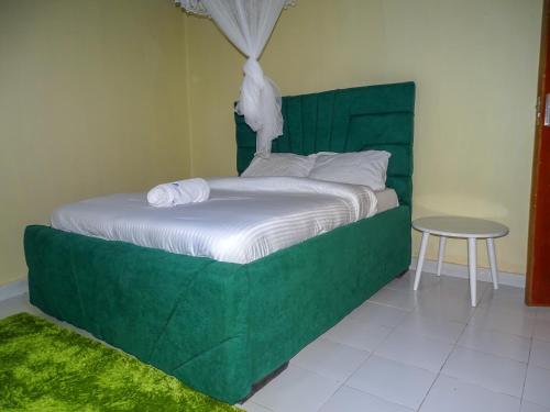 un lit avec une tête de lit verte et une table dans l'établissement Nash Issah Green- Milimani Nakuru-1Bedroom, à Nakuru
