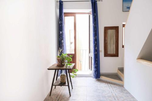 a hallway with a blue doorway and a table with a plant at Lipari - Casa Centro Storico in Lipari