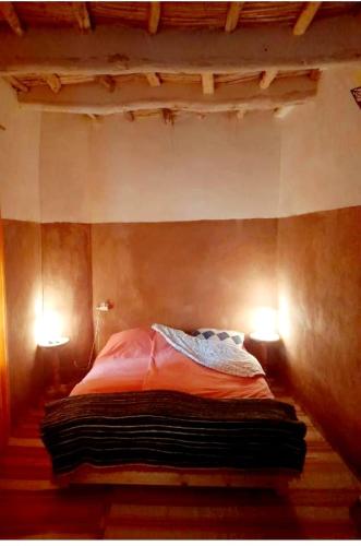 a bed in a room with two lights on it at Noé Nomade , chambre privé in Sidi Bou Othmane