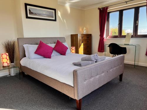 a bedroom with a large bed with pink pillows at 4 Bed Farmhouse - Pets - Garden - Parking in Beaumaris