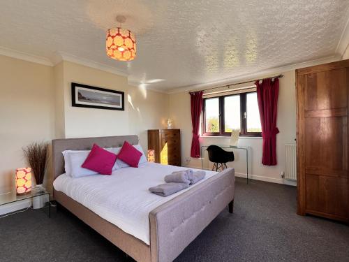 um quarto com uma cama grande e almofadas cor-de-rosa em 4 Bedroom Detached Farmhouse Mountain Views em Beaumaris