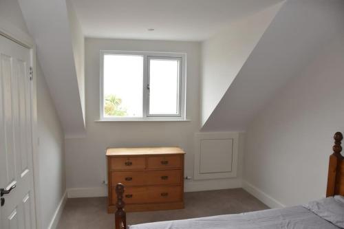 a bedroom with a bed and a dresser and a window at Luxurious apartment near the sea in Dun Laoghaire