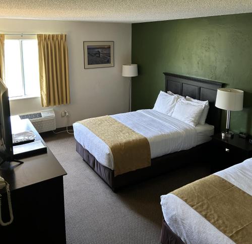 a hotel room with two beds and a television at Boarders Inn & Suites by Cobblestone Hotels - Munising in Wetmore