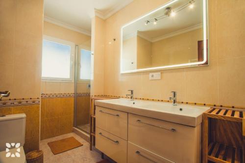 ein Badezimmer mit einem Waschbecken, einem Spiegel und einem WC in der Unterkunft Villa Sea Breeze by Abahana Villas in Benitatxell