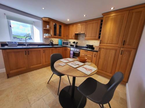 eine Küche mit Holzschränken, einem Holztisch und Stühlen in der Unterkunft Grange Cottage in Aysgarth