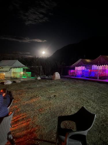a night view of a field with tents and a chair at Nubra ethnic camp in Nubra