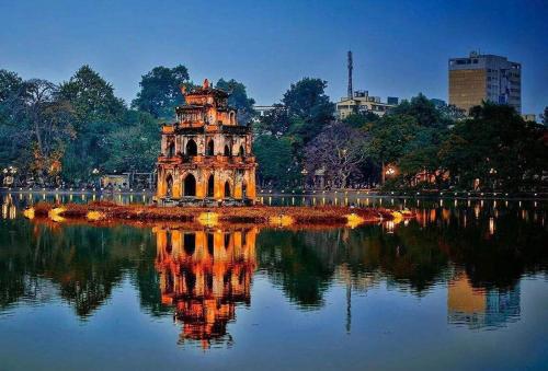 a building in the middle of a lake at night at Sen's Cozy House - 02 Queen beds - Kitchen - Center of Old Quarter, Hoan Kiem district in Hanoi