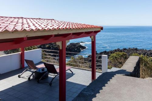 a gazebo with two chairs and the ocean at Cantinho dos Cagarros in Lajes do Pico