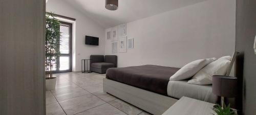 a white bedroom with a bed and a chair at B&B Domus San Pietro in Cetara