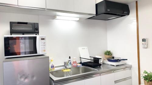 a kitchen with a sink and a microwave at Spring Apartment Shinjuku in Tokyo