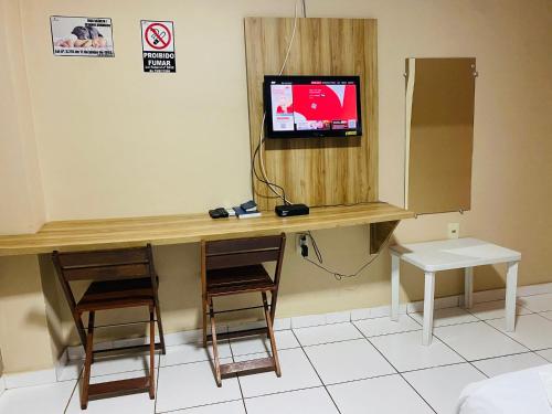 a room with a desk with two chairs and a tv at Borges Hotel in Imperatriz