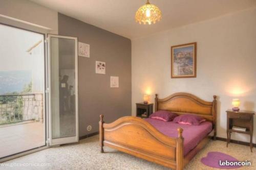 a bedroom with a wooden bed and a balcony at 95m2 au calme à 25mn AJACCIO, plages, linge inclus parking ok in Ucciani