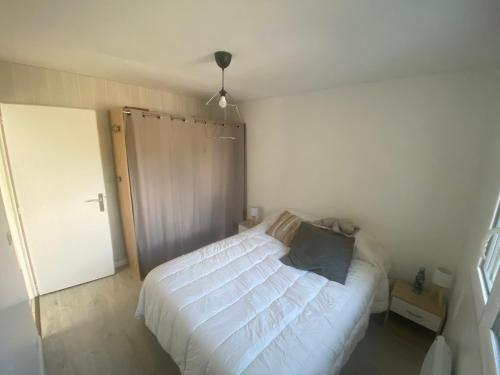 1 dormitorio con cama blanca y puerta corredera en Villa T3 au calme, en Le Teich