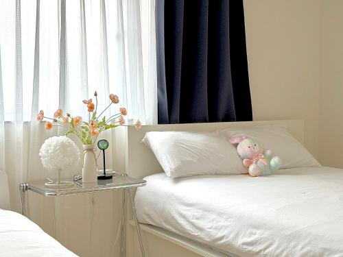 a white bed with a stuffed animal on a pillow at Sadang Greennarae Stay in Seoul