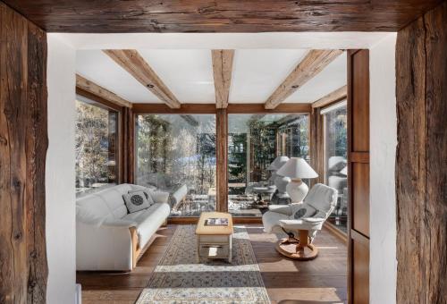 una sala de estar con muebles blancos y ventanas grandes. en Chalet Cinq Moutons, en Orsières