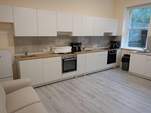 a kitchen with white cabinets and a sink and a couch at Dublin Palm 2 Shared rooms in Dublin