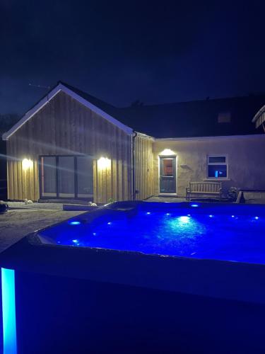 una piscina azul frente a una casa por la noche en Barnaby’s Barn, en Carmarthen
