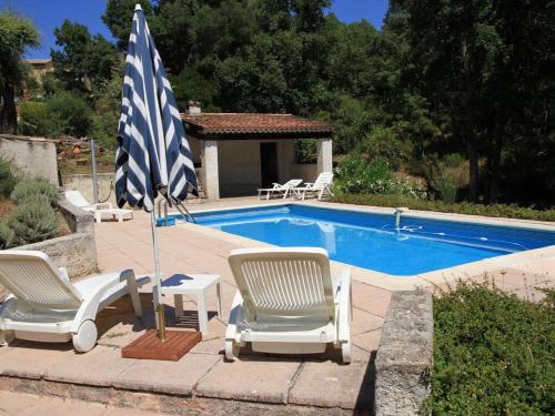- une piscine avec 2 chaises longues et un parasol dans l'établissement Villa LA PIBOULE, à Bagnols-en-Forêt