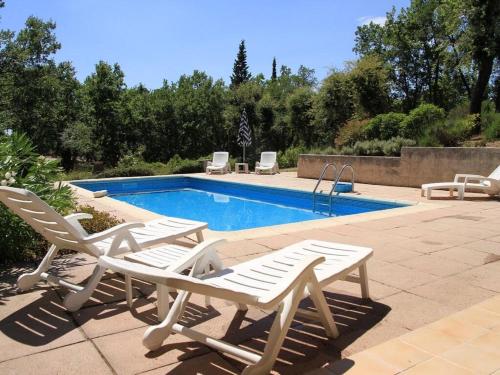 - une piscine avec 2 chaises longues à côté dans l'établissement Villa LA PIBOULE, à Bagnols-en-Forêt