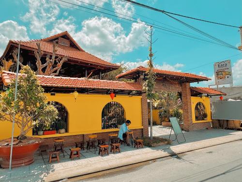 a man sitting in front of a yellow building at Kara Homestay & Cafe in Can Tho