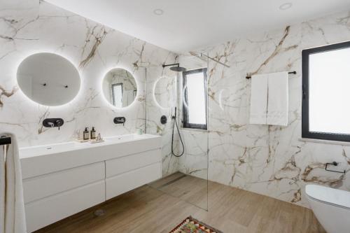 Villa Oceânica في ألبوفيرا: حمام به جدران من الرخام وحوض استحمام ومغسلة