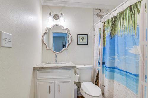 ein Badezimmer mit einer weißen Toilette und einem Spiegel in der Unterkunft Walk to Beach and Moody Mansion Galveston Home! in Galveston