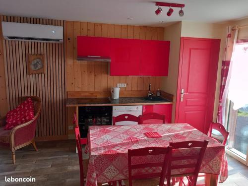 una cocina con armarios rojos y una mesa con sillas. en Le chalet des Patures, en Rochefort-Montagne