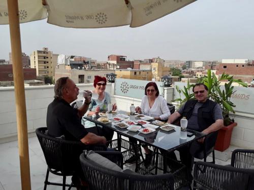 un gruppo di persone seduti intorno a un tavolo su un tetto di Aurora Pyramids Hotel a Il Cairo