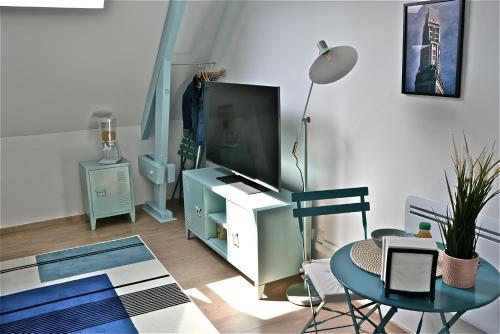 un salon avec une télévision et une table dans l'établissement 400m gare&centre ville, sèche linge, local vélo, à Amiens
