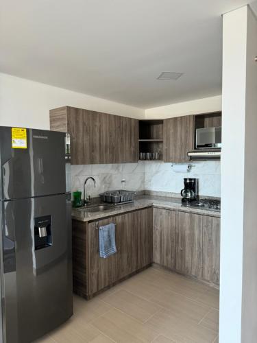 a kitchen with wooden cabinets and a stainless steel refrigerator at Alojamiento en El Carmen de Viboral in Carmen de Viboral