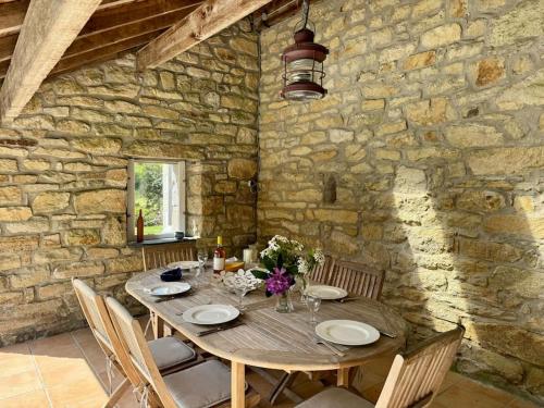 a wooden table in a room with a stone wall at La Ferme, spacieuse maison tout confort, Bénodet in Bénodet