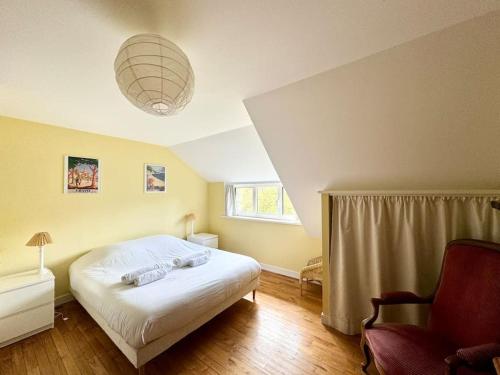 une chambre avec un lit et une chaise dedans dans l'établissement La Ferme, spacieuse maison tout confort, Bénodet, à Bénodet