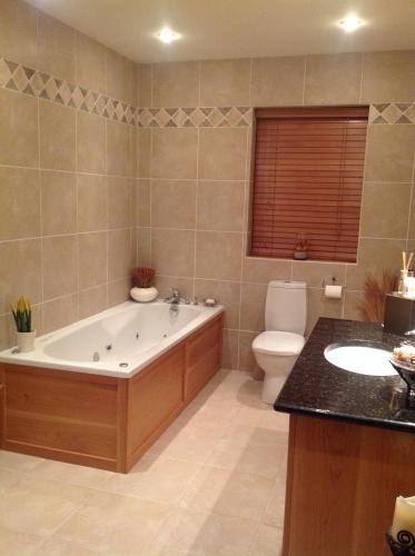 a bathroom with a tub and a toilet and a sink at 4 bedroom holiday home overlooking the sea in Connemara in Rossaveel