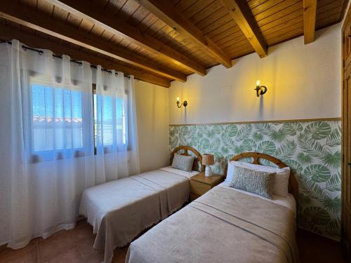 two beds in a room with a window at Complejo Rural Los Cachos in Baterna