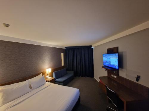a hotel room with a bed and a flat screen tv at Holiday Inn Express Lisbon Airport, an IHG Hotel in Lisbon